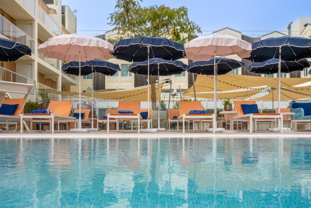 una piscina con sillas y sombrillas y una piscina en Mercure La Rochelle Vieux Port, en La Rochelle