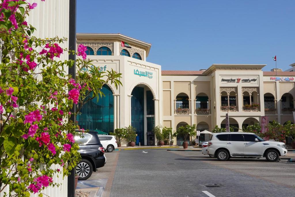a large building with cars parked in a parking lot at Andalus Al Seef Resort & Spa in Abu Dhabi