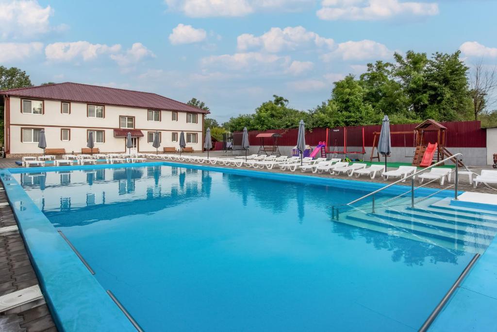 a large swimming pool with chairs and umbrellas at Ранчо Офре in Solotvyno