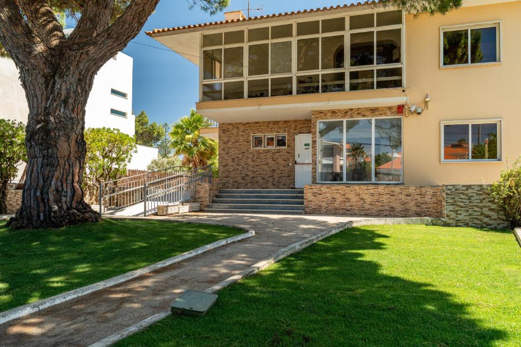 a house with a tree in front of it at Lisbon Surf Hostel in Carcavelos