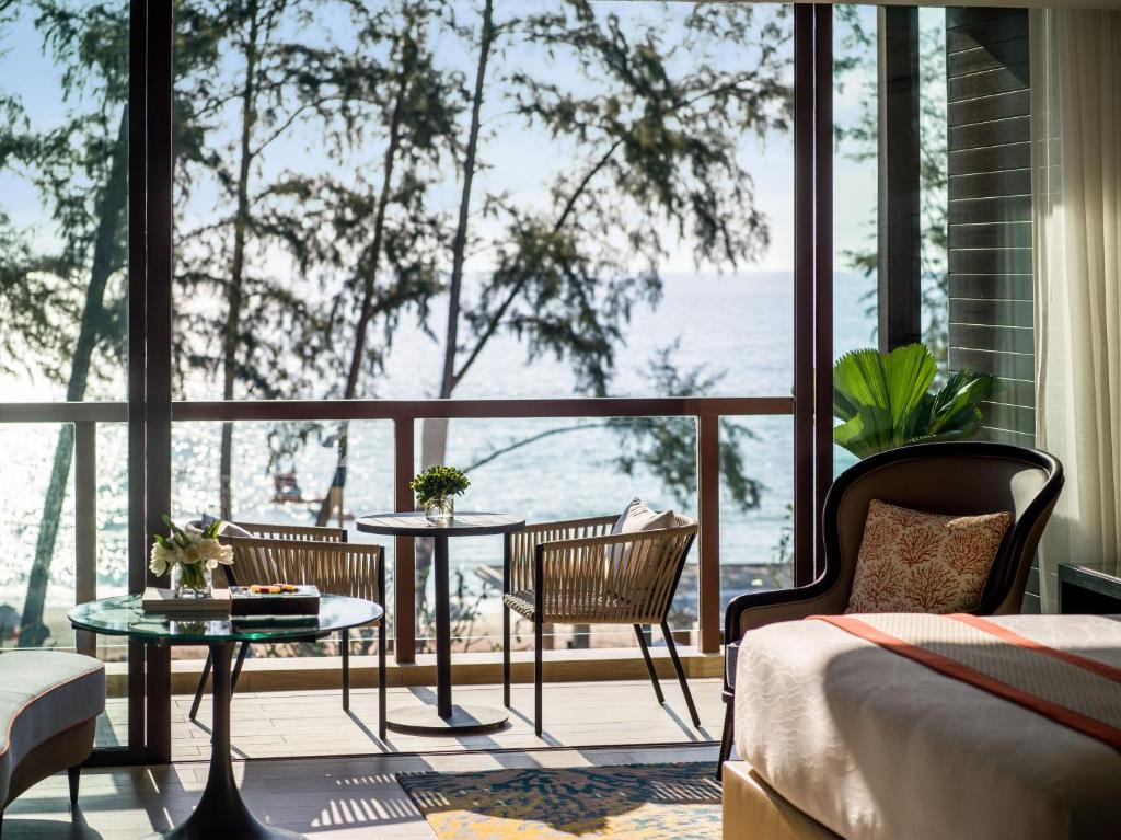 a room with a large window with a table and chairs at InterContinental Phuket Resort by IHG in Kamala Beach