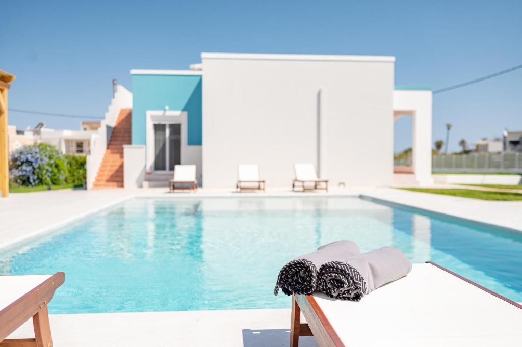 a hat and a hat sitting on a chair next to a swimming pool at Villa Eos Mastichari - with heated pool in Mastichari