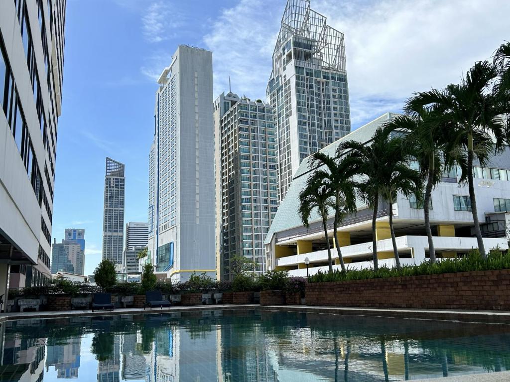 a pool in the middle of a city with tall buildings at Royal Benja Hotel in Bangkok