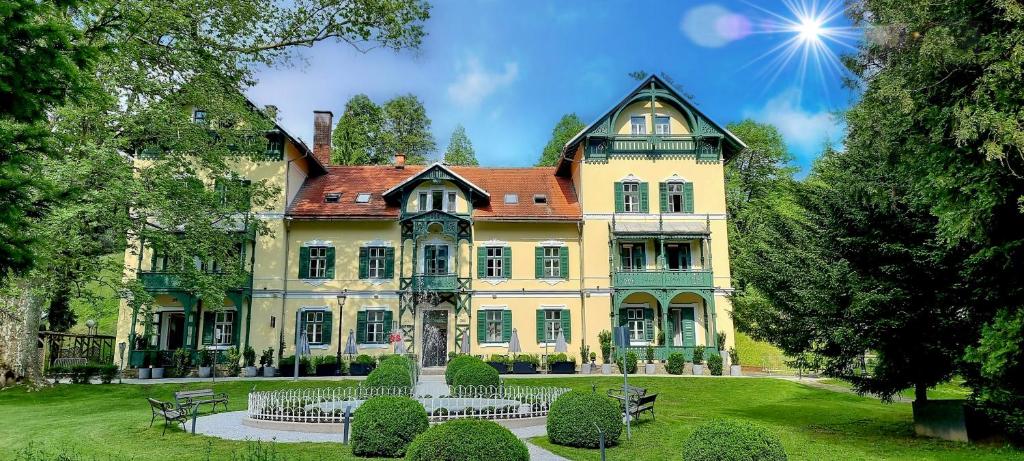 una gran casa amarilla con techo rojo en Hotel Švicarija - Terme Dobrna, en Dobrna