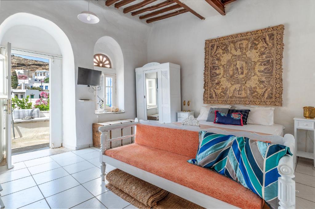 a bedroom with a bed with an orange bench at Platia Tinos Cycladic Cottage in Platiá