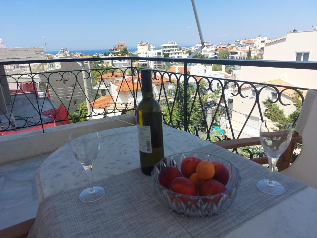- une bouteille de vin et un bol de fruits sur une table dans l'établissement Sea view,big and comfortable appartment in Voula, à Athènes