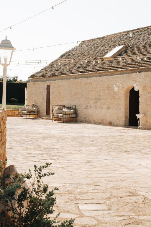 a brick building with a courtyard with two benches at San Marco Antico Relais - B&B in Bitonto
