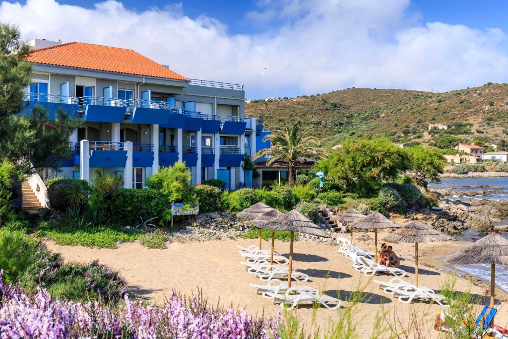 Best Western Premier Santa Maria في ليل روس: مبنى ازرق على الشاطئ وبه كراسي ومظلات