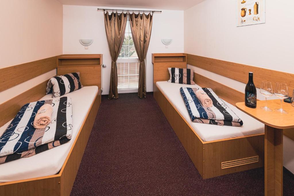 a room with two beds and a table with wine glasses at Vinné sklepy Skalák in Skalka