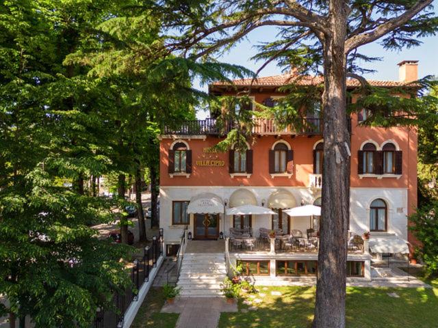 a large brick house with tables and chairs in front of it at Hotel Villa Cipro in Venice-Lido