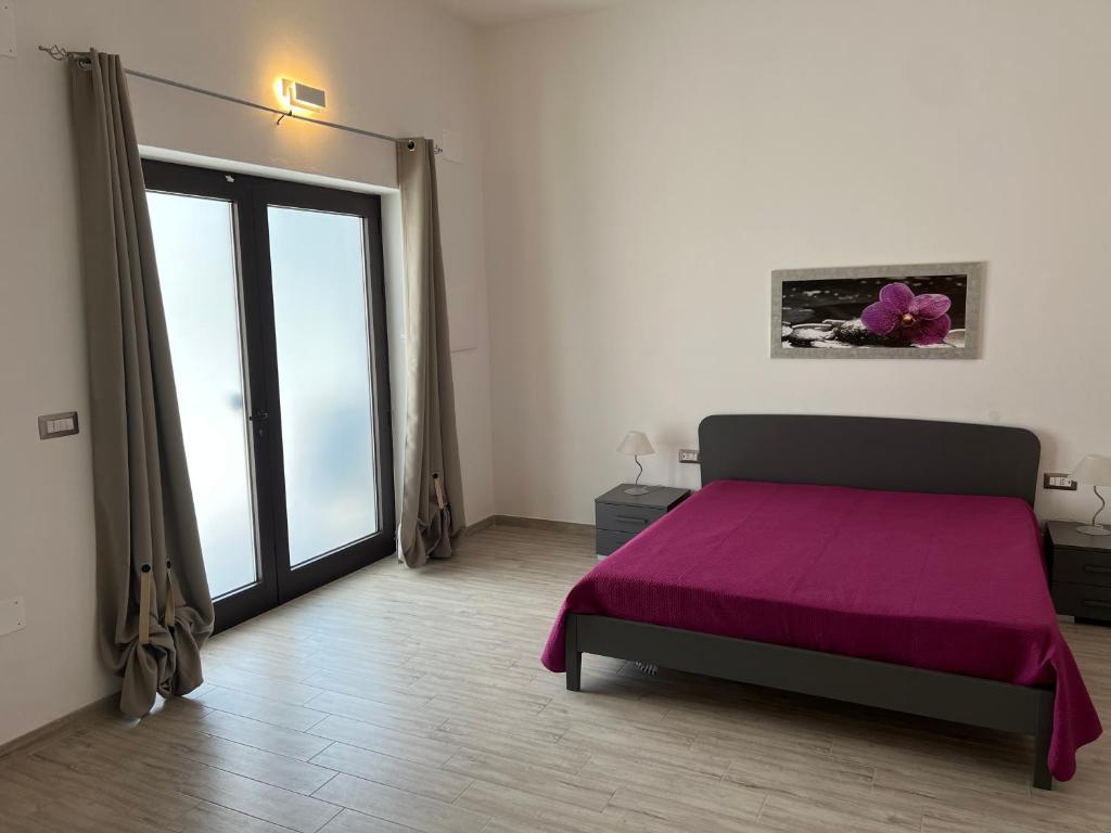 una camera con un letto viola e una grande finestra di Residenza Giulia a Scanzano