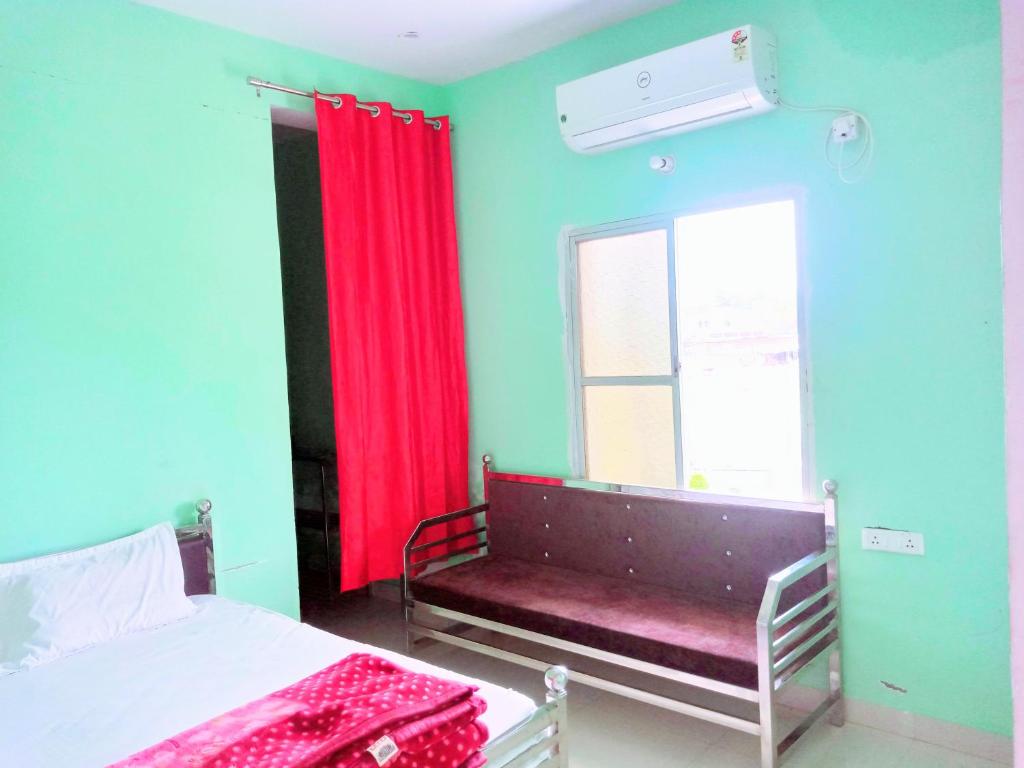 Hotel Parvati Residency في Sītāpur Mūāfi: غرفة نوم بسرير ونافذة ذات ستارة حمراء