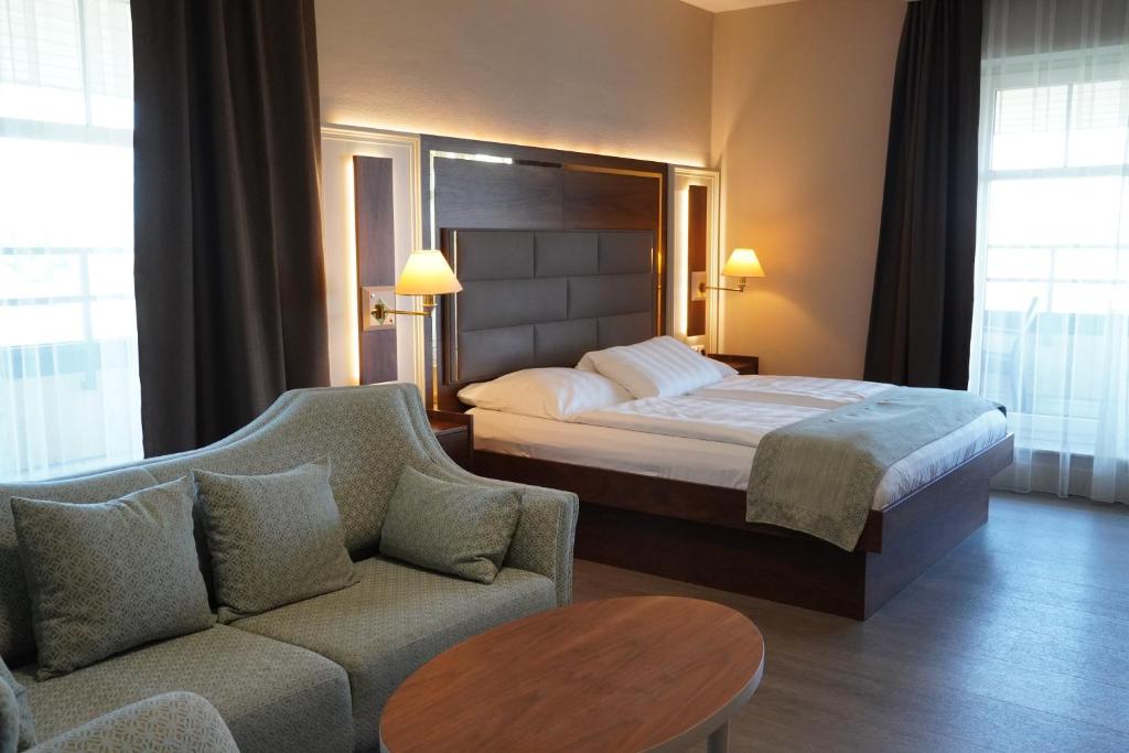 バート・フィルベルにあるシティ ホテル フランクフルト バート フィルベルのベッドとソファ付きのホテルルーム