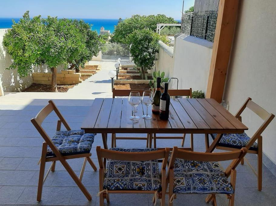 a wooden table and chairs with wine bottles and glasses at Casa vacanze Gemini in Triscina
