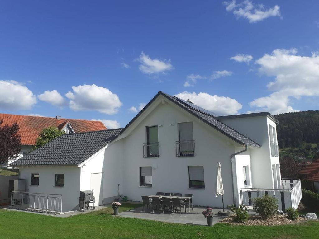 Cette maison blanche dispose d'une terrasse et d'une table. dans l'établissement Dorfglück Oberdigisheim, à Meßstetten