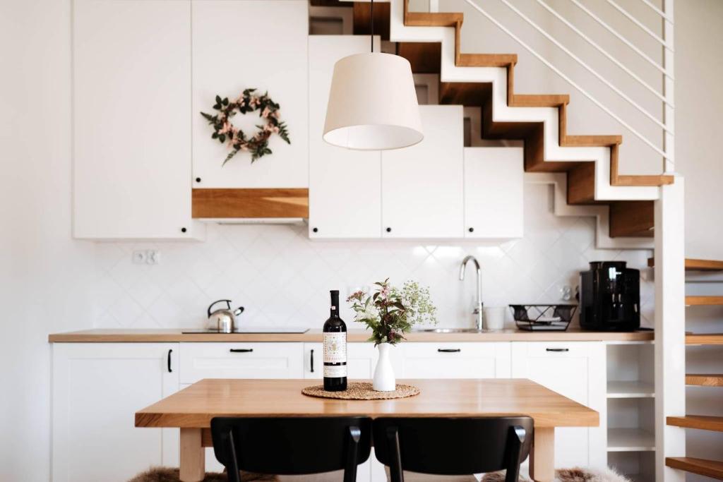 a kitchen with white cabinets and a table with a bottle of wine at Domek pod Szarowym lasem in Wisła