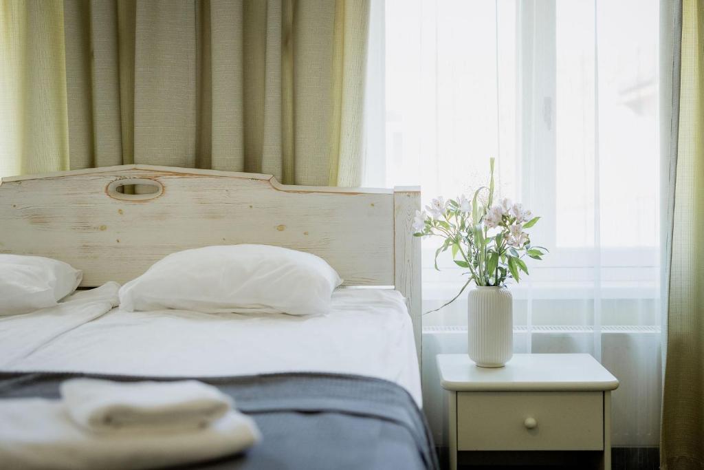 a bed with two white pillows and a vase with flowers at Vanalinna Boutique Hotel in Kuressaare