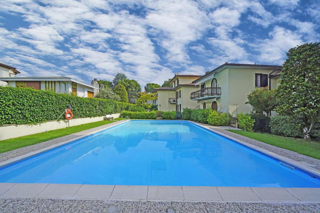 a blue swimming pool in front of a house at Appartamento Mazzini P1-25 by Wonderful Italy in Sirmione