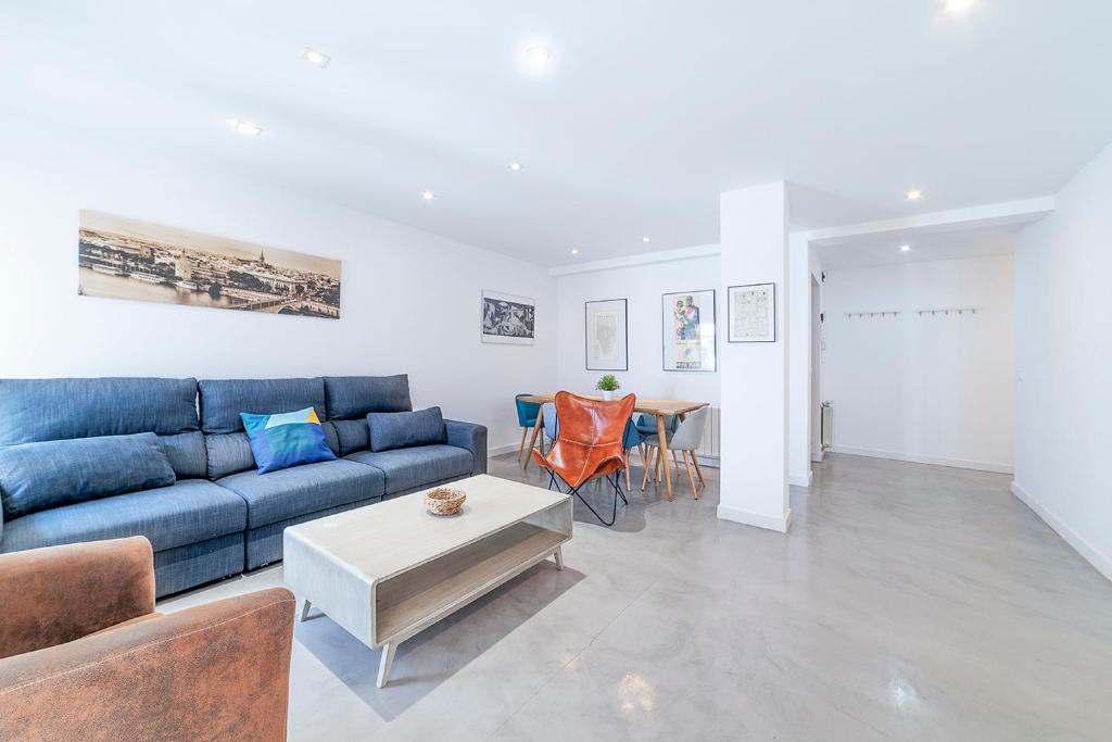 ein Wohnzimmer mit einem blauen Sofa und einem Tisch in der Unterkunft AlohaMundi Corral del Rey in Sevilla