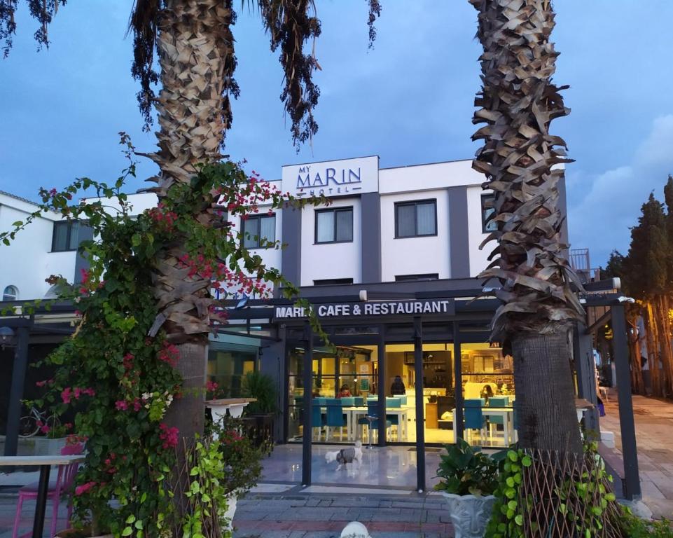 un restaurante con dos palmeras delante en My Marin Otel, en Turgutreis
