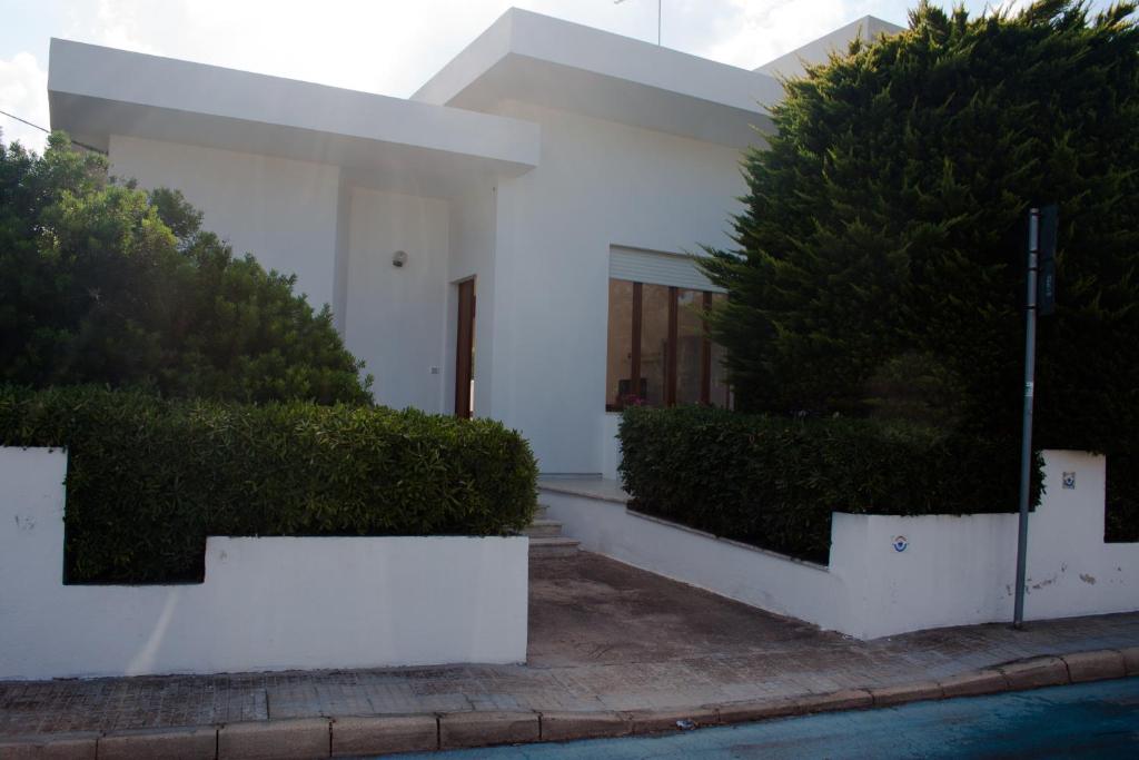 une maison blanche avec un grand bush devant elle dans l'établissement Casa Arco, à Torre Suda