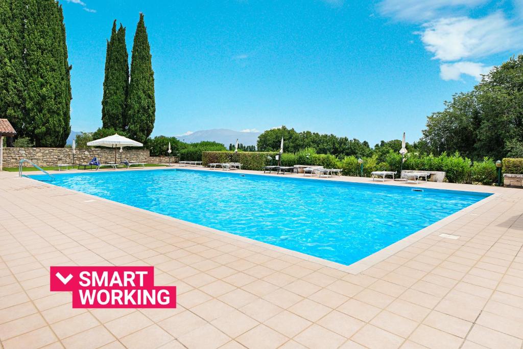 a large swimming pool in a yard with trees at Birdie 59 Apartment by Wonderful Italy in Soiano del Lago
