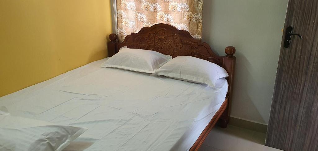um quarto com uma cama com lençóis brancos e almofadas em Hallima Service Apartments Home Stay purpose Guest House 4 em Pudukkottai