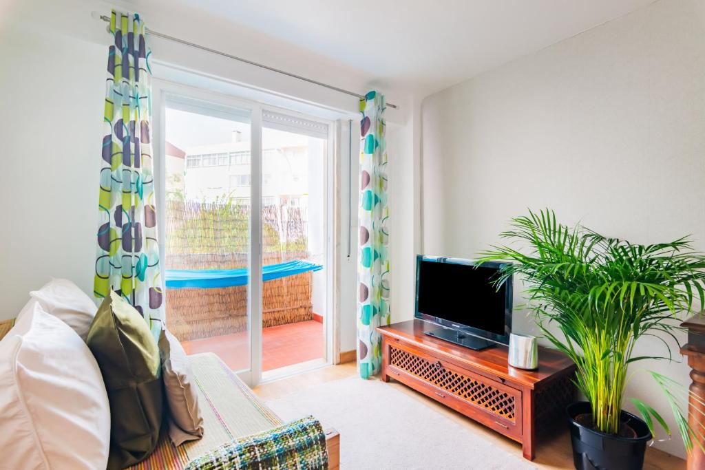 ein Wohnzimmer mit Sofa und Fernseher in der Unterkunft Santo Amaro Beach Family Stays in Oeiras