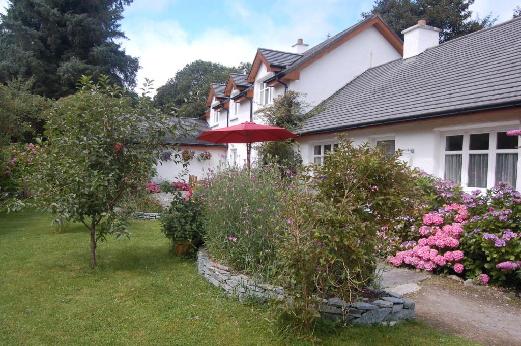 a house with a garden of flowers and an umbrella at Beaufort Lodge B&B & Cottage in Beaufort