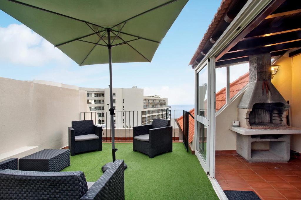 a patio with chairs and an umbrella on a balcony at Penthouse Vista Mar in Funchal