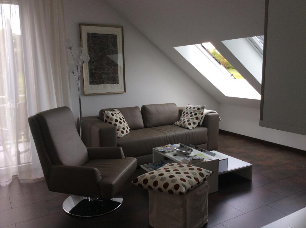 a living room with a couch and a chair at 2-Zimmer-Ferienwohnung mit Hotelservice und 2 Balkons - Golf, Bike und Wellness im Markgräflerland in Bad Bellingen