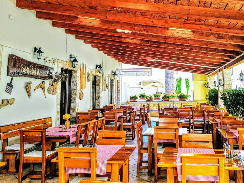 ein Restaurant mit Holztischen und Holzstühlen in der Unterkunft Villa Palčić II in Novalja