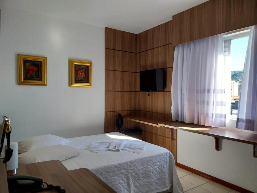 a hotel room with a bed and a window at Colle Tourist Hotel in Criciúma