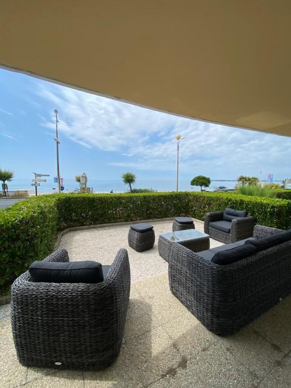 un groupe de chaises et de poufs en osier sur une terrasse dans l'établissement Horizon Bleu : Appartement Vue Mer à La Baule, à La Baule