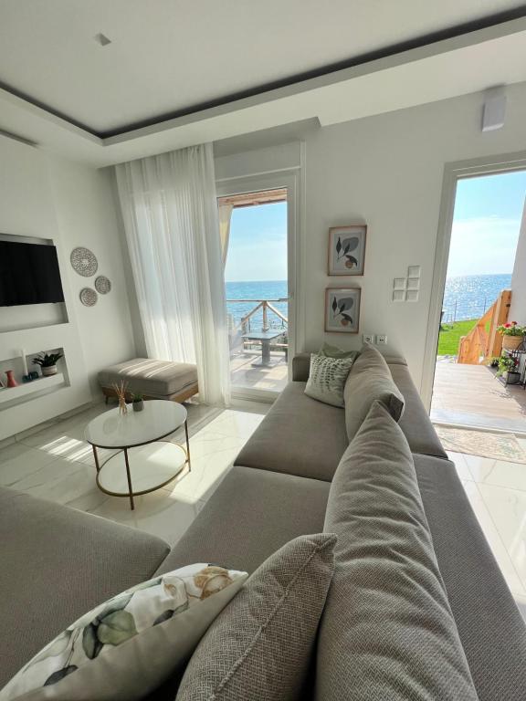 Beachfront Villa Athina في Vergia: غرفة معيشة مع أريكة وإطلالة على المحيط