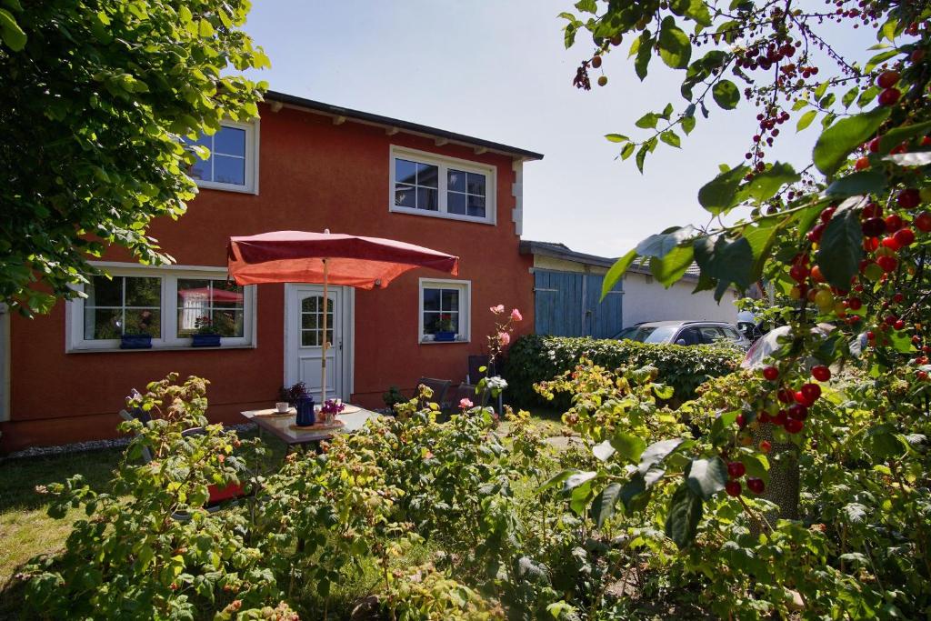 a red house with an umbrella in the yard at zentral aber ruhig, Terrasse mit viel Grün - strandnahes Ferienhaus Luki in Göhren