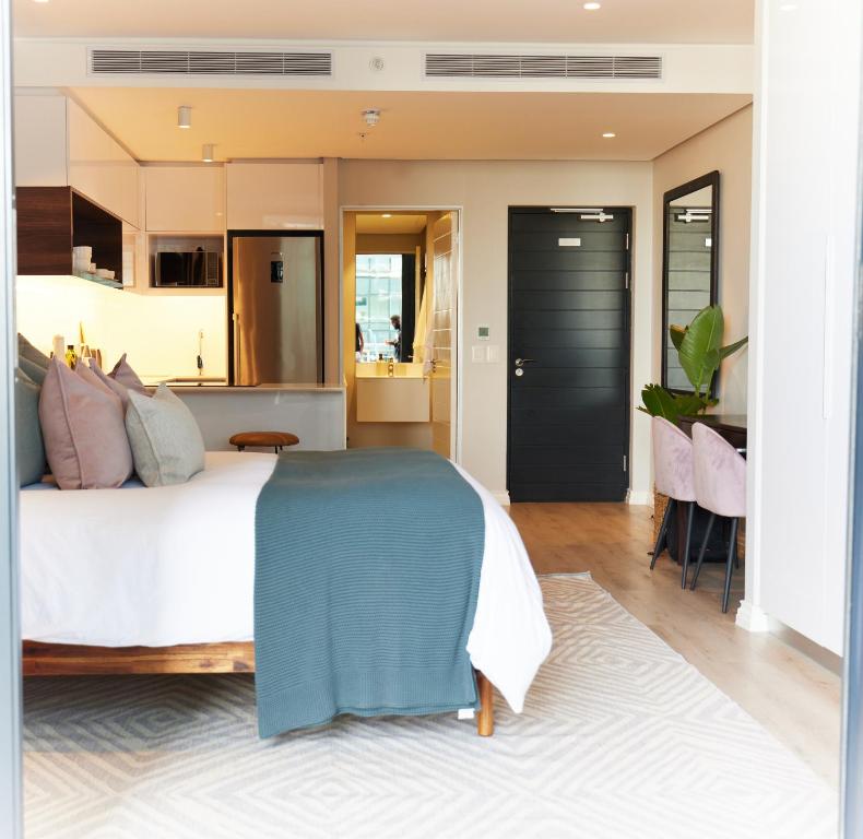 a bedroom with a large bed and a kitchen at Stunning 12th floor apartment with private balcony at 16onBree in Cape Town