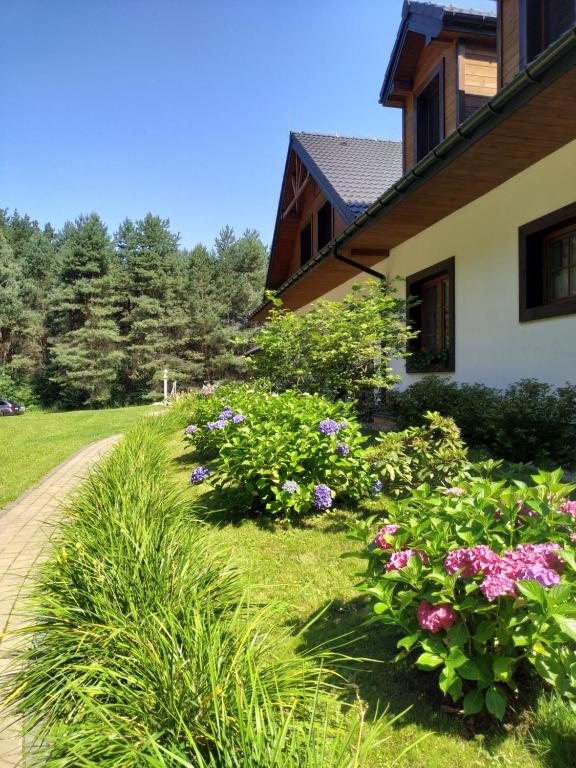 a garden with flowers next to a house at Majątek Morgi in Suchowola