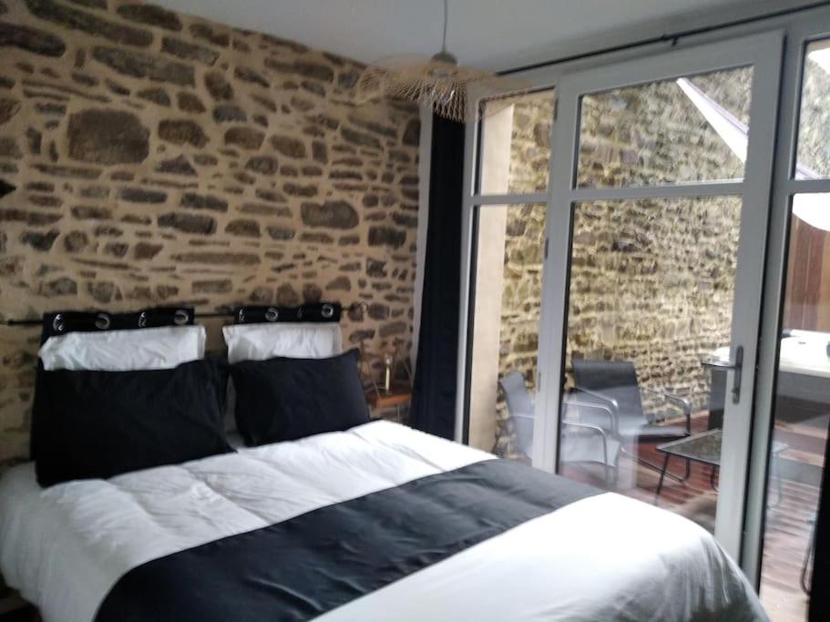 Cama en habitación con pared de ladrillo en Charmant logement avec jacuzzi, en Fougères