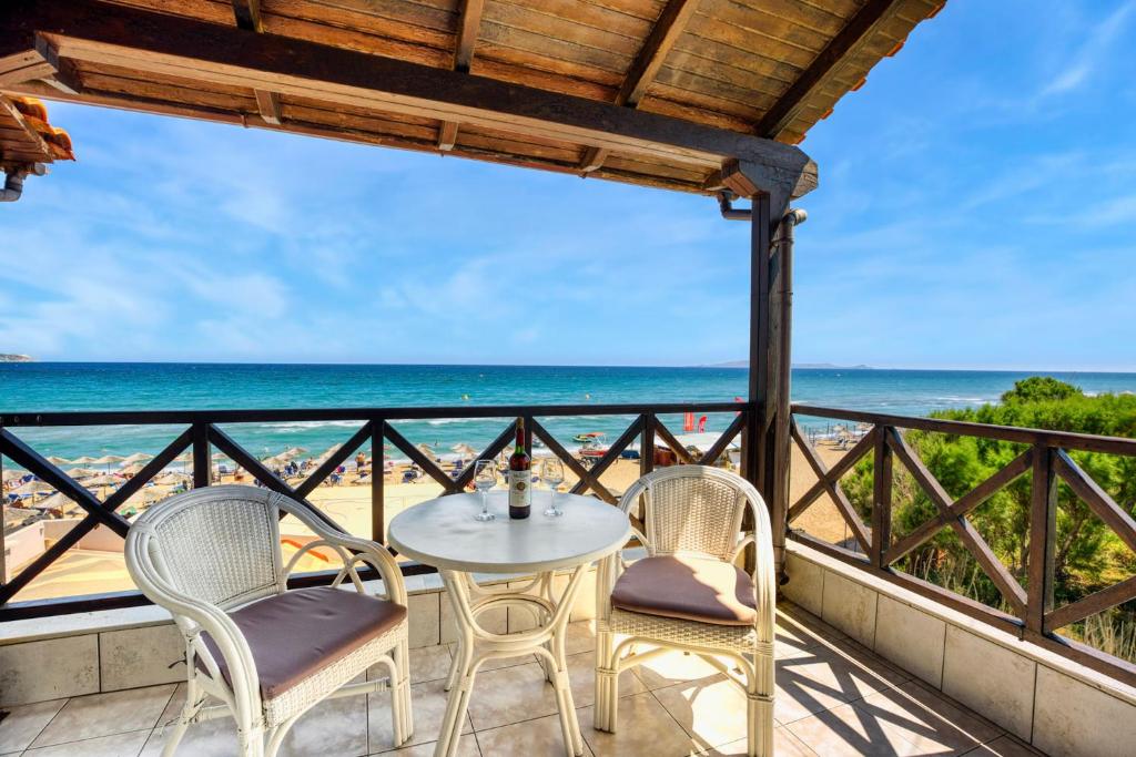 um pátio com uma mesa e cadeiras e o oceano em Troulis Seaside em Amoudara Herakliou