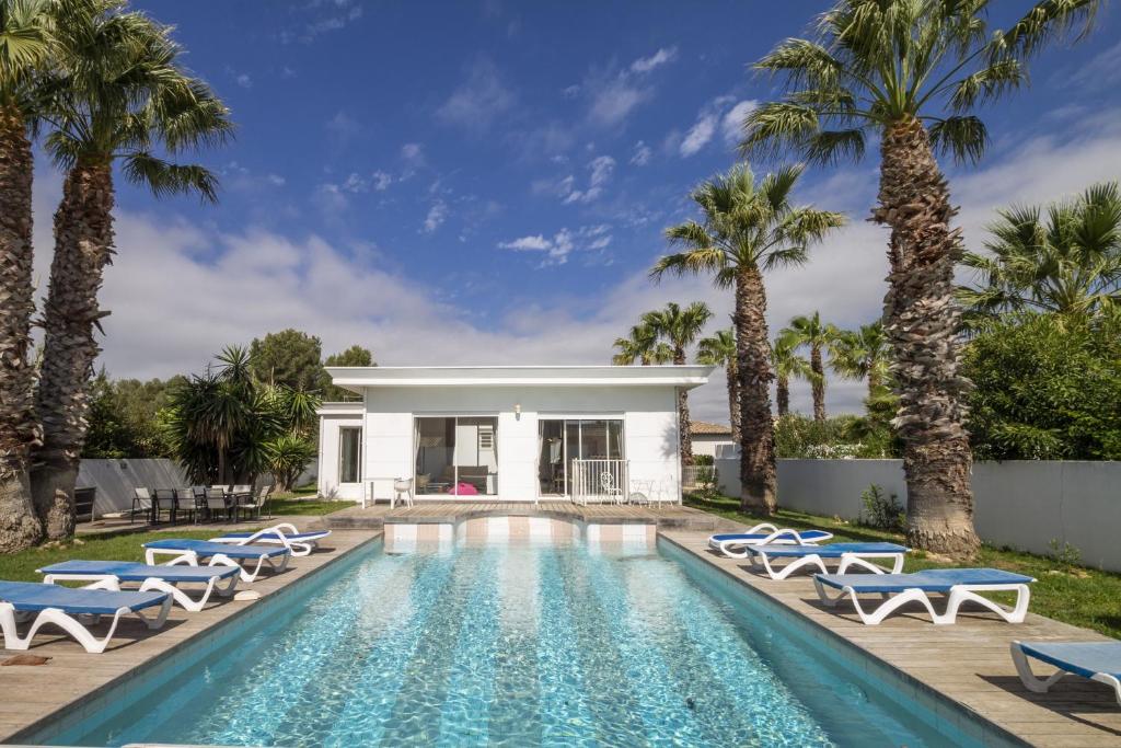 a swimming pool with lounge chairs and palm trees at Envie de Vivre in Agde