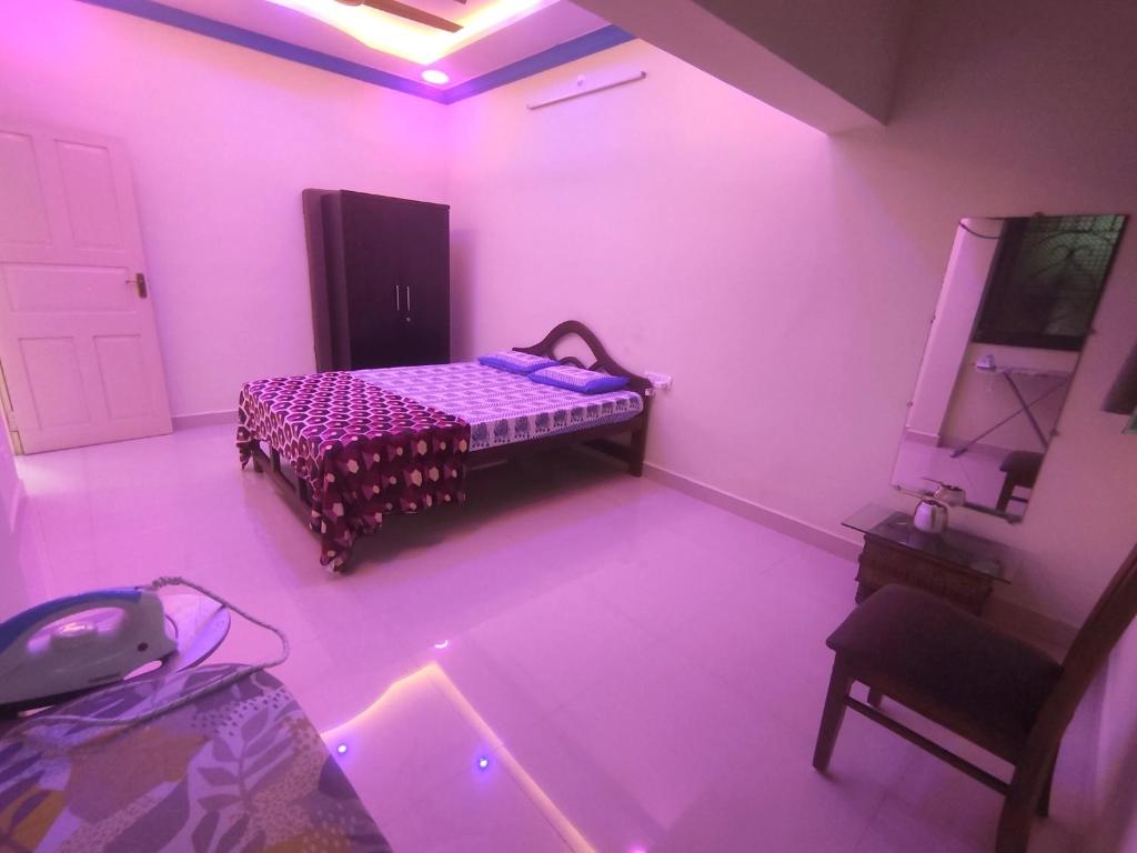 Serene Homestay في باناجي: غرفة نوم مع سرير في غرفة مع أضواء وردية