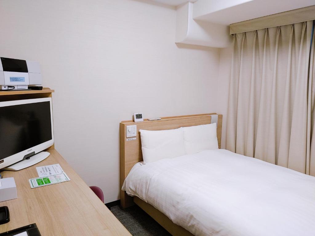 a hotel room with a bed and a television at Dormy Inn Express Matsue in Matsue