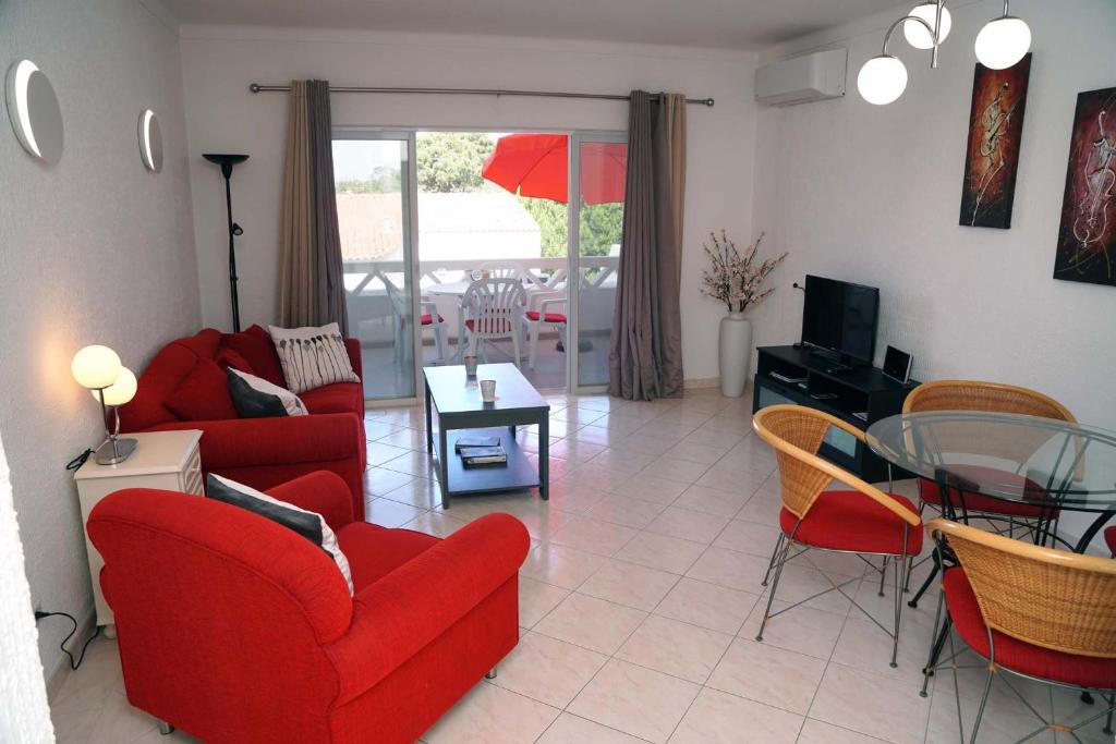 uma sala de estar com cadeiras vermelhas e uma mesa de vidro em 2 bedroom apartment in Vale do Lobo em Vale do Lobo
