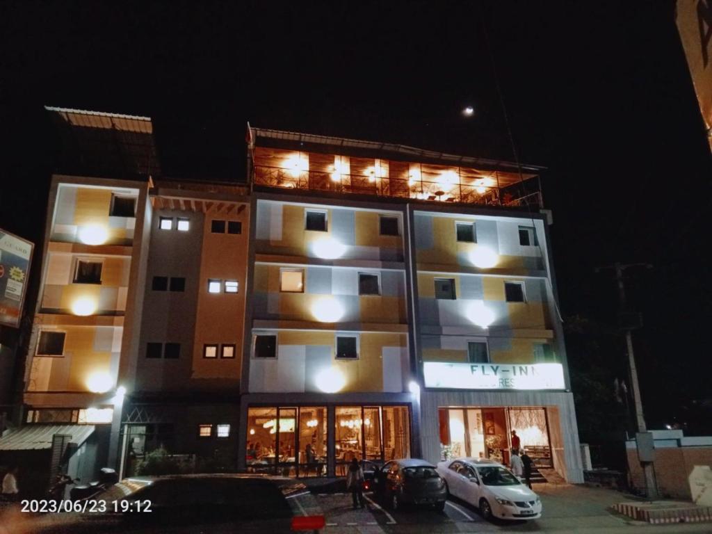 Un grand bâtiment avec des voitures garées devant lui dans l'établissement FLY INN Madagascar HOTEL - Navette GRATUITE H24 - à 300m de l'Aéroport International Ivato-Antananarivo, à Ivato