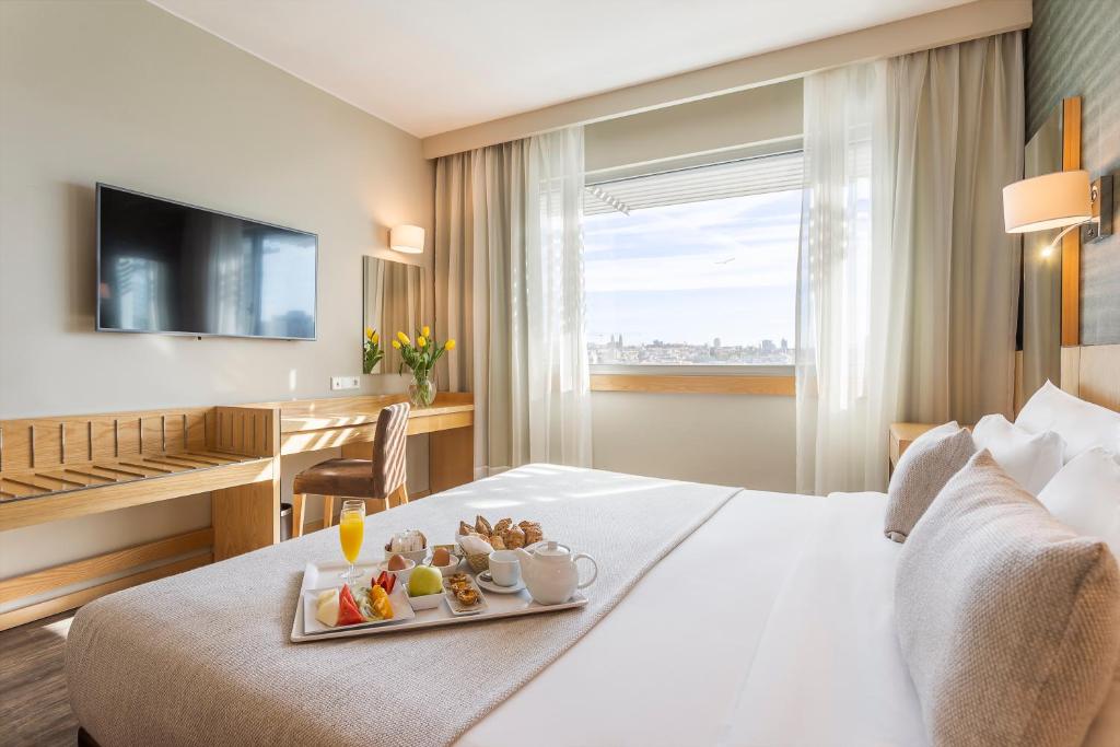 une chambre d'hôtel avec un plateau de nourriture sur un lit dans l'établissement HF Ipanema Porto, à Porto