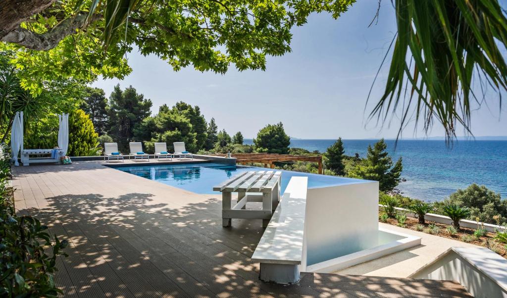 a swimming pool with a bench next to the ocean at SEA VIEW Ranch By the Sea in Vatopedi