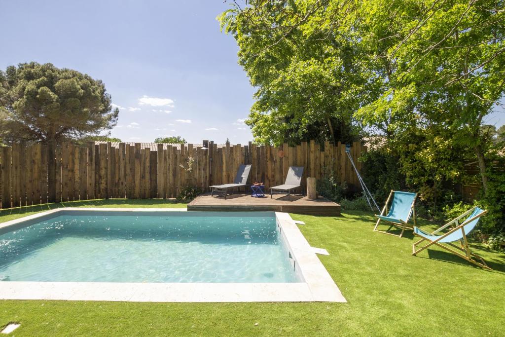 - une piscine dans une cour à côté d'une clôture en bois dans l'établissement Le Dali, à Piolenc