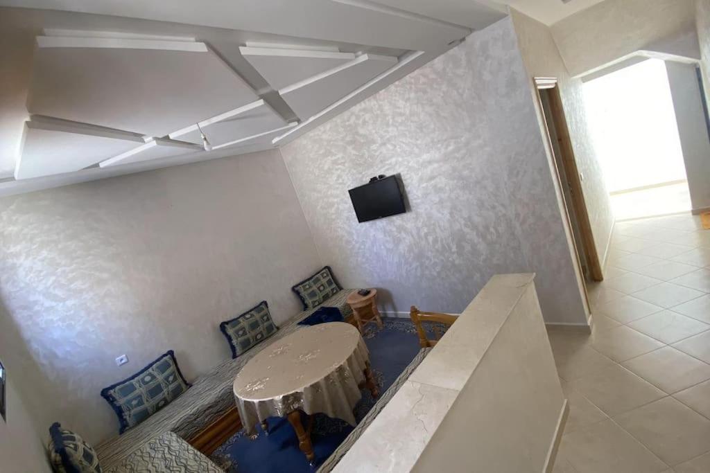 een kamer met een tafel en stoelen en een televisie bij Superbe appartement neuf in Agadir