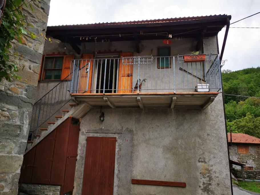 ein altes Gebäude mit einem Balkon und einer Treppe in der Unterkunft Casa immersa nella natura in Capanne di Sillano